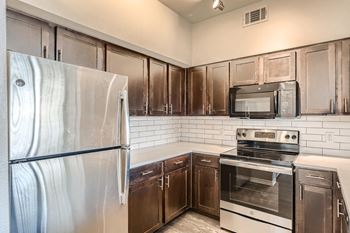 A kitchen with a stainless steel refrigerator, microwave, and oven at Fox Run Lofts Apartments, Englewood Colorado.